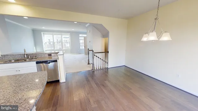 a view of a kitchen with granite countertop a stove top oven a sink a dishwasher with wooden floor and cabinets