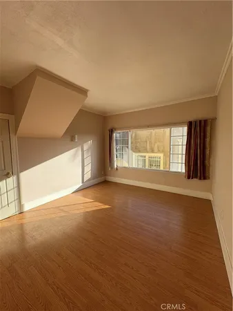 a view of an empty room with a window and wooden floor