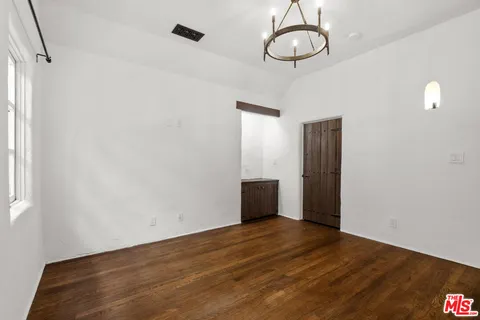 a view of an empty room with wooden floor and window