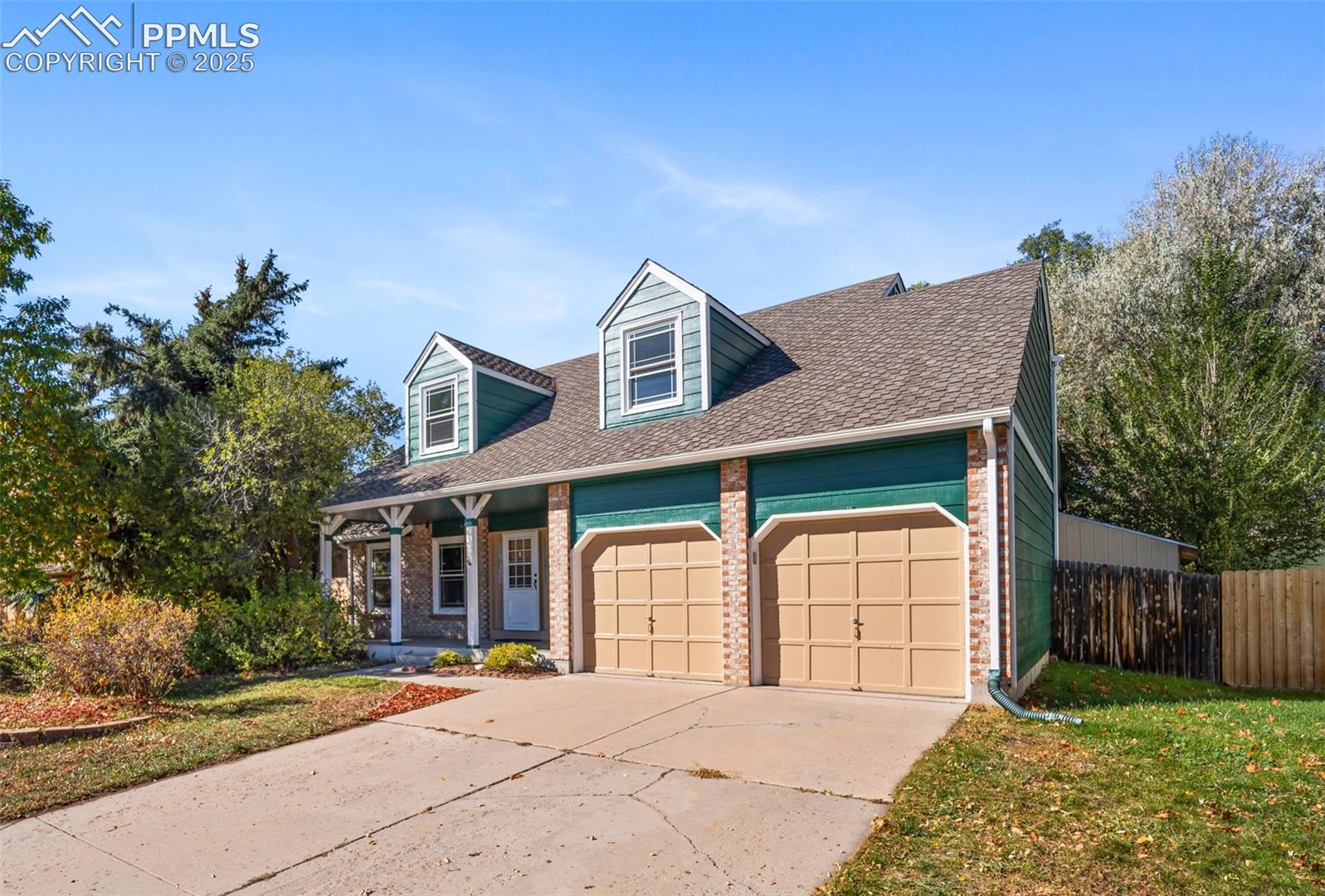 103 Saddlemountain Road Colorado Springs, CO 80919 - Photo 1 of 30 Cape cod house featuring roof with shingles, brick siding, driveway, a garage, and a porch
