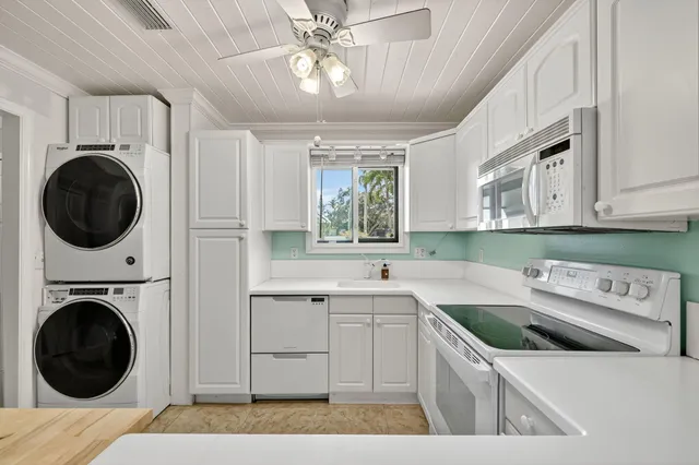 an empty room with chandelier fan and windows