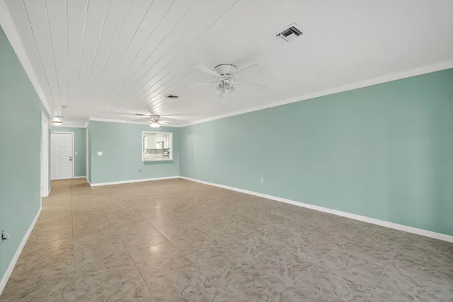 an empty room with chandelier fan and windows