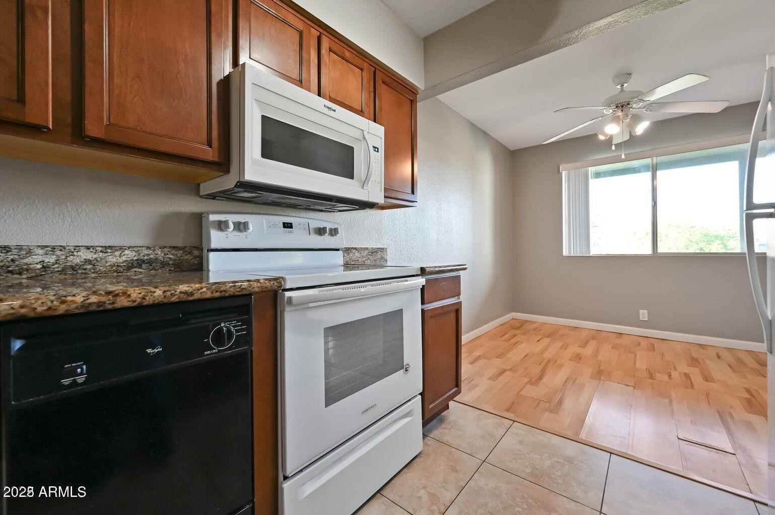 1702 West Tuckey Lane, Unit 212 Phoenix, AZ 85015 - Photo 11 of 20 a kitchen with stainless steel appliances granite countertop a stove a sink and a microwave