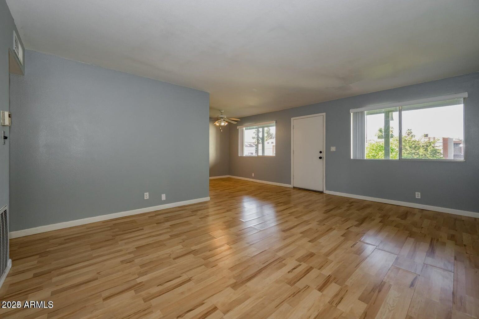 1702 West Tuckey Lane, Unit 212 Phoenix, AZ 85015 - Photo 14 of 20 an empty room with wooden floor and windows