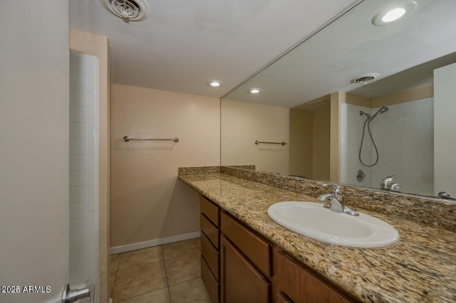 1702 West Tuckey Lane, Unit 212 Phoenix, AZ 85015 - Photo 15 of 20 a bathroom with a granite countertop sink a mirror and a shower