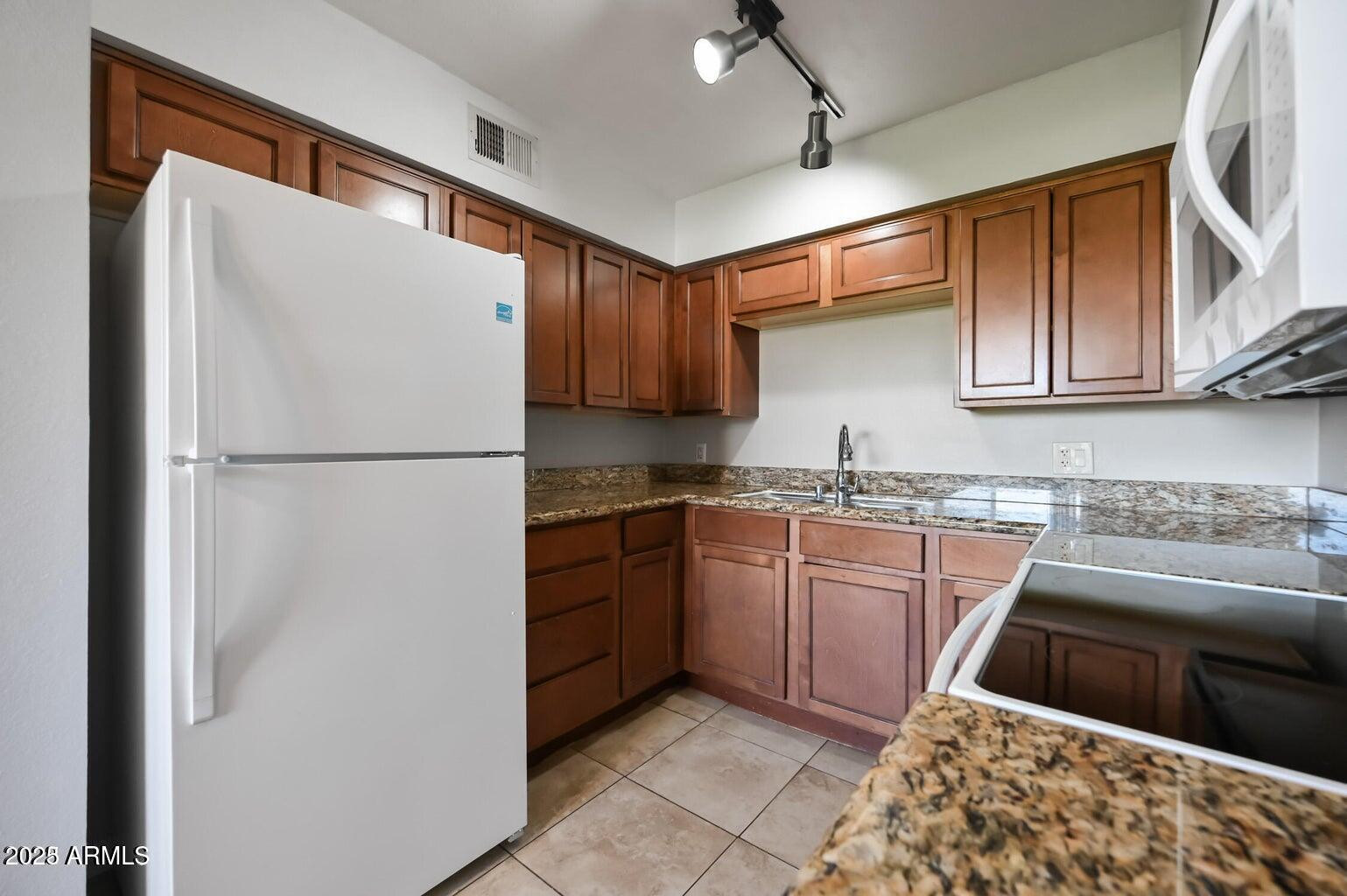 1702 West Tuckey Lane, Unit 212 Phoenix, AZ 85015 - Photo 10 of 20 a kitchen with stainless steel appliances granite countertop a refrigerator a sink and a stove