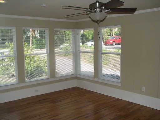 a view of an empty room with wooden floor and windows
