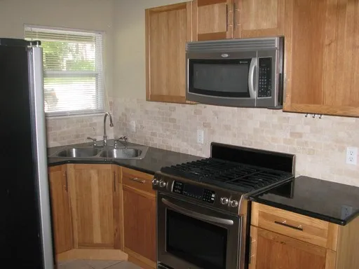 a kitchen with granite countertop a stove top oven cabinetry a sink and a window