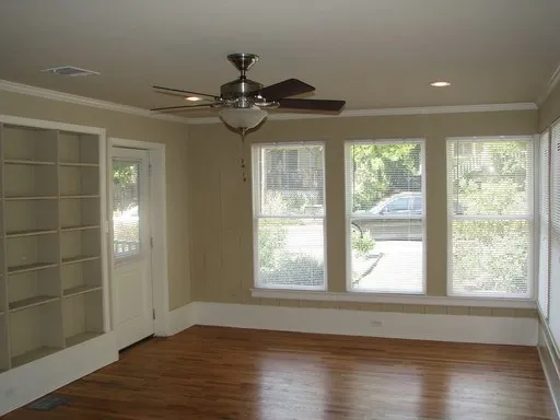 a view of an empty room with wooden floor and a window