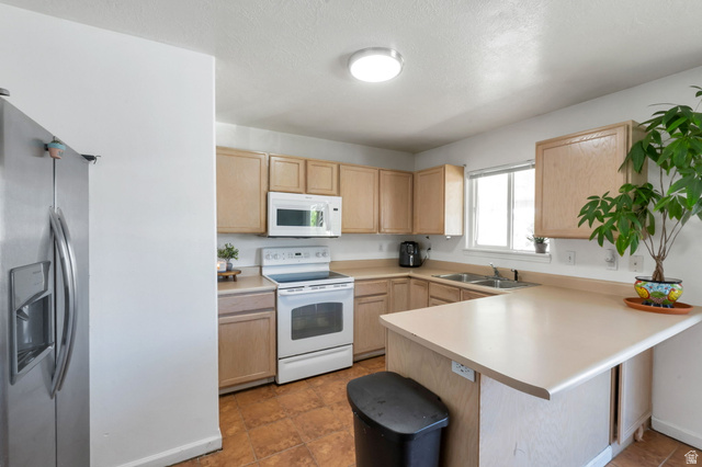 2013 West 460 South Provo, UT 84601 - Photo 9 of 24 Kitchen featuring a stainless steel refrigerator, white oven, overhead microwave, light wood-finish cabinetry, and a double basin sink