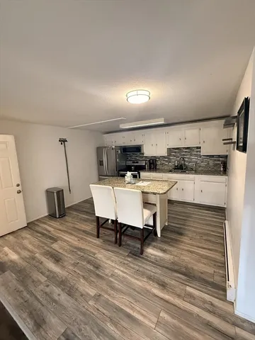 a living room with stainless steel appliances kitchen island granite countertop furniture and a fireplace