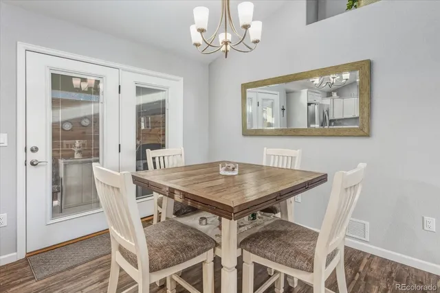 a kitchen with stainless steel appliances granite countertop a dining table chairs refrigerator and microwave