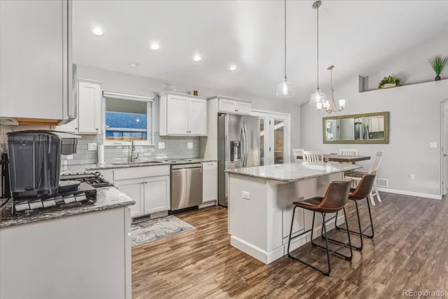 a kitchen with kitchen island granite countertop a sink cabinets and stainless steel appliances