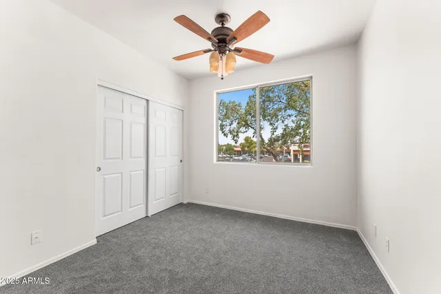 an empty room with a window and a fan