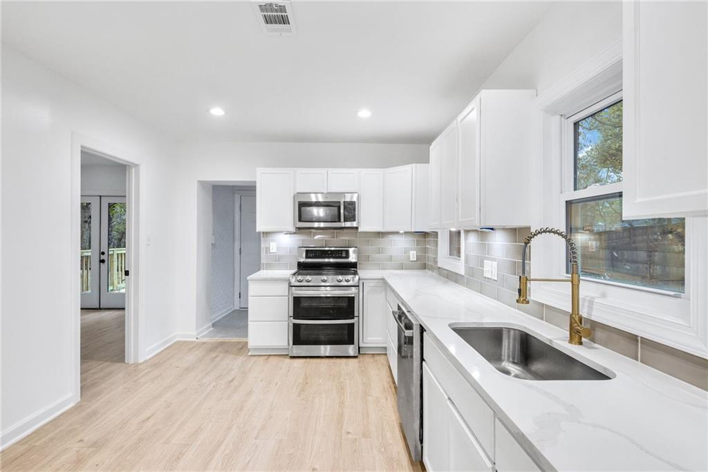 1967 Browns Mill Road Southeast Atlanta, GA 30315 - Photo 12 of 35 a kitchen with granite countertop a sink wooden floor and stainless steel appliances