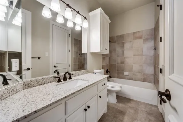 a bathroom with a granite countertop sink mirror toilet and bathtub