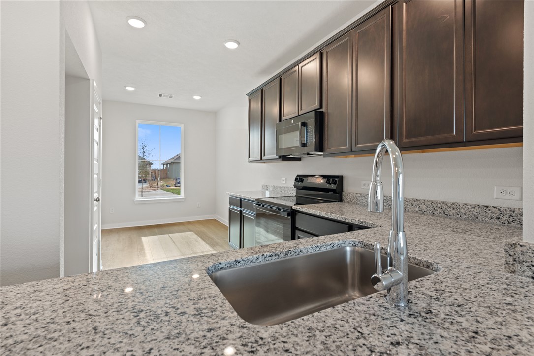 2412 Rooke Road Bryan, TX 77807 - Photo 13 of 35 a kitchen with stainless steel appliances granite countertop a sink a stove and a refrigerator