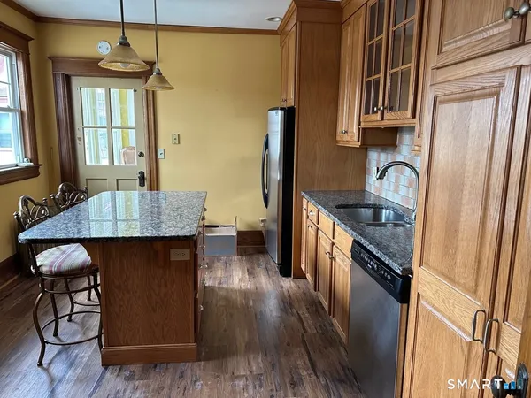 a kitchen with granite countertop a stove a sink a refrigerator and wooden floor