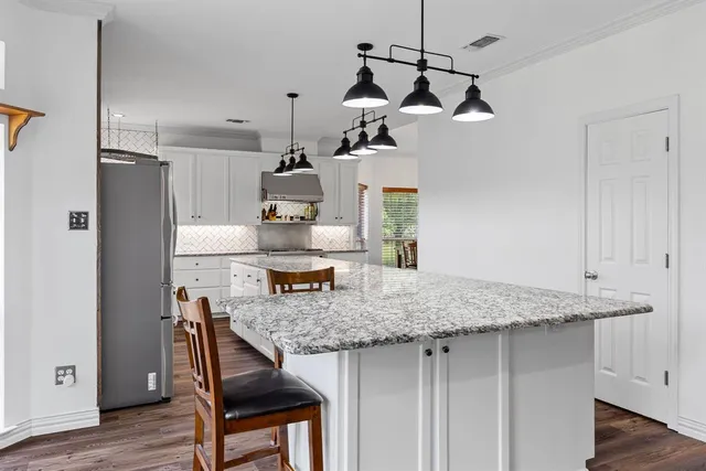 a kitchen with a table chairs refrigerator and wooden floor