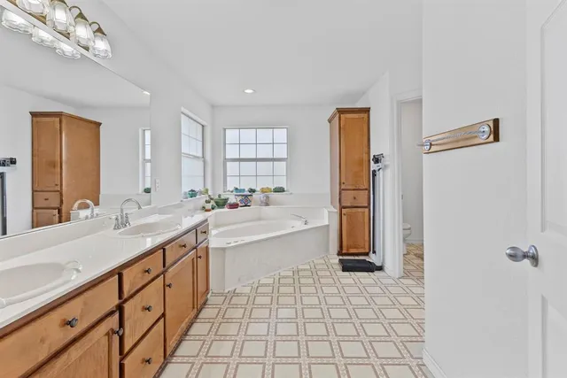 a large bathroom with a granite countertop sink a mirror and a bathtub