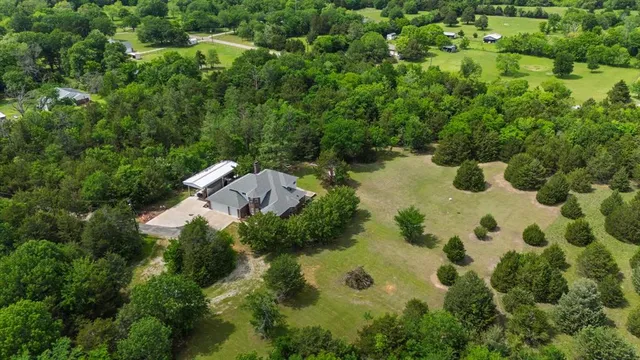 an aerial view of residential house with outdoor space and trees all around