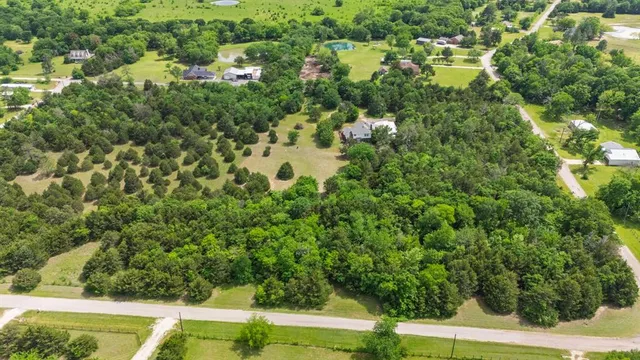 an aerial view of residential house with outdoor space and trees all around