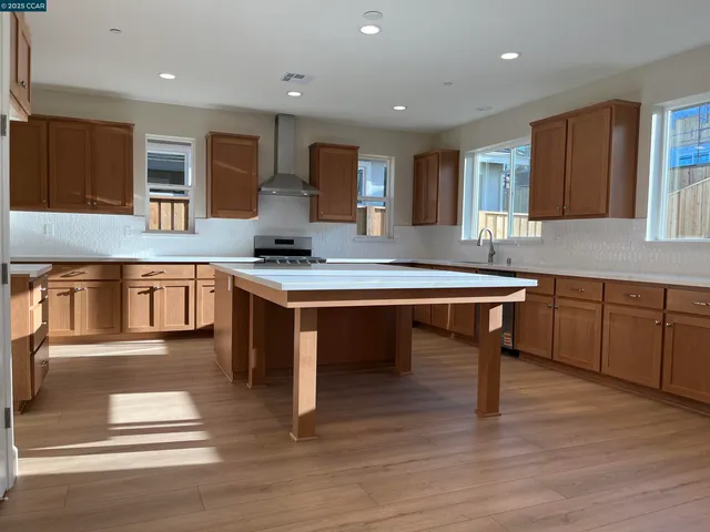 a kitchen with stainless steel appliances granite countertop a kitchen island hardwood floor sink stove dining table and chairs