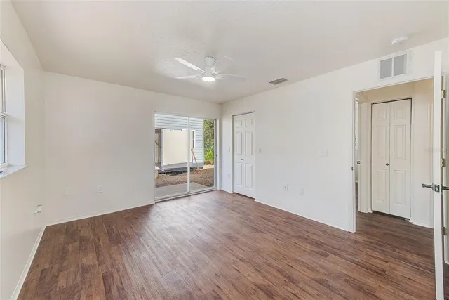 an empty room with wooden floor and a ceiling fan