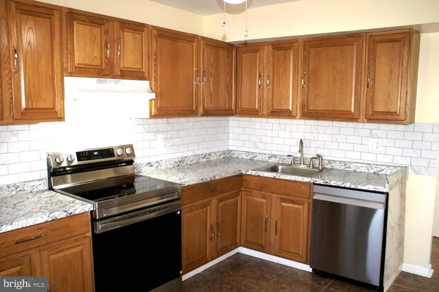 a kitchen with granite countertop a sink stove and cabinets