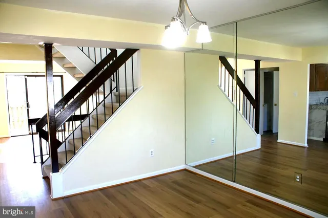 a view of a hallway with wooden floor staircase and a living room