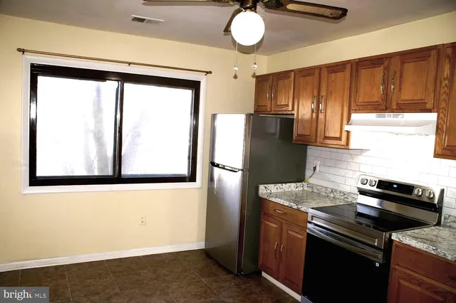 a kitchen with stainless steel appliances granite countertop a refrigerator a stove and a sink with wooden floor