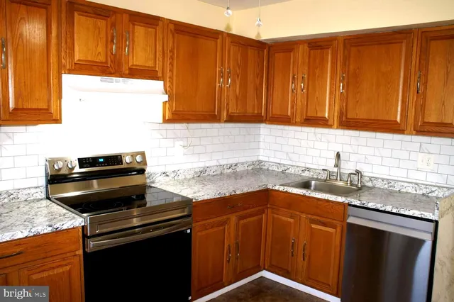 a kitchen with granite countertop wooden cabinets and a stove top oven