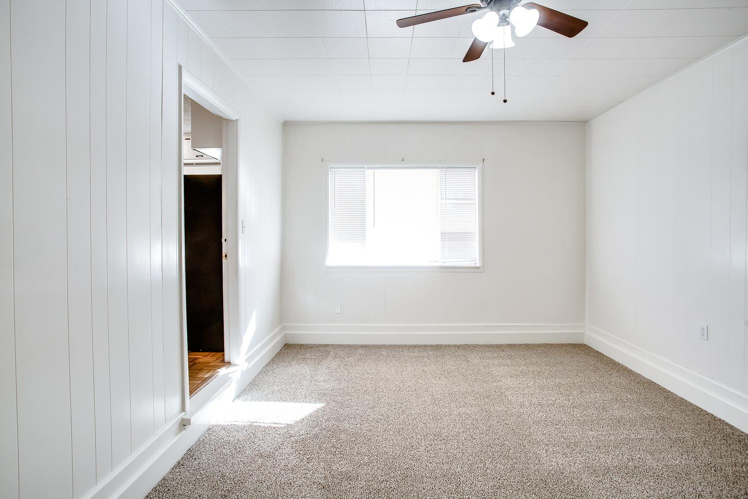 3414 32nd Street Lubbock, TX 79410 - Photo 5 of 11 an empty room with a chandelier fan and windows