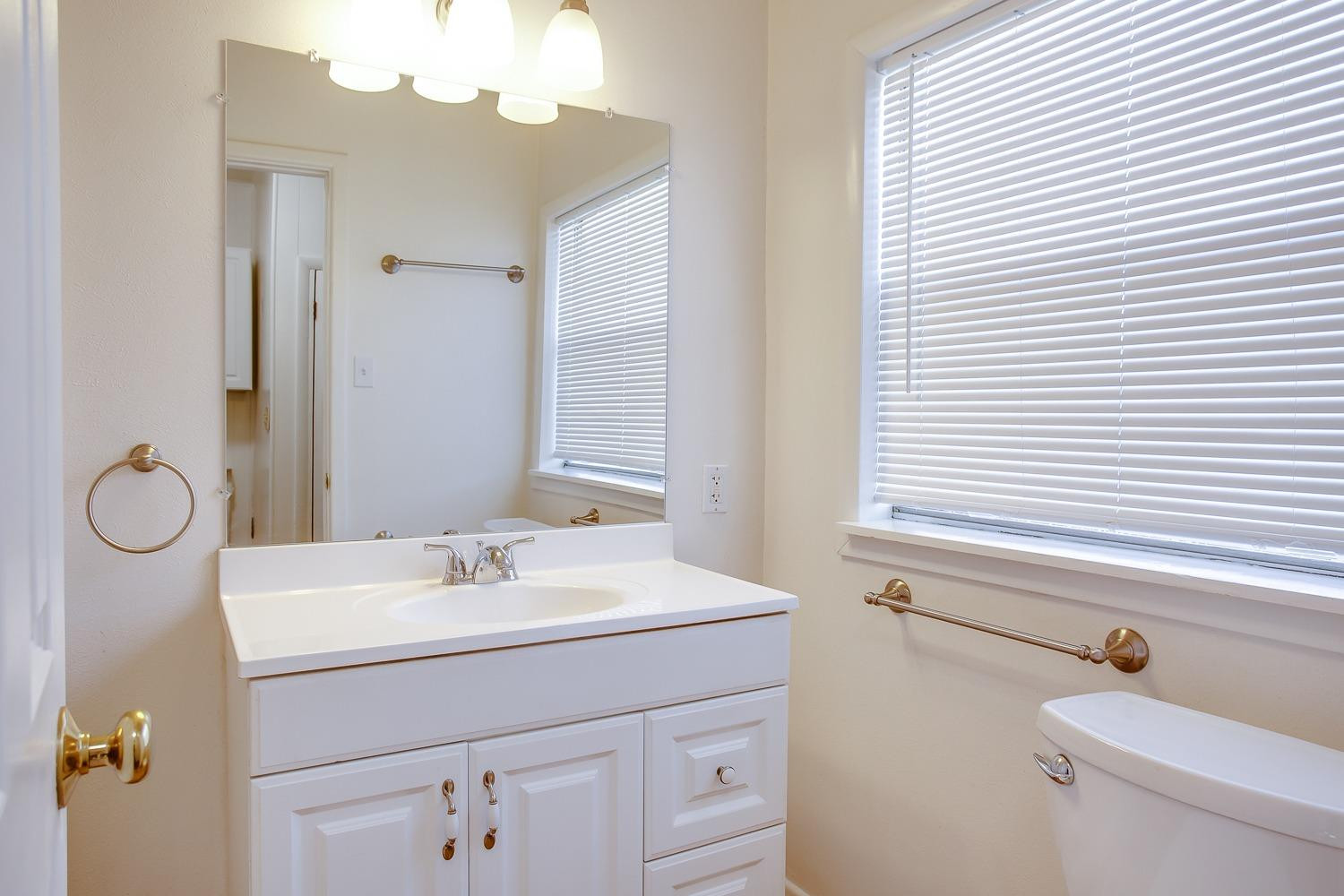 3414 32nd Street Lubbock, TX 79410 - Photo 6 of 11 a bathroom with a sink a toilet and a mirror