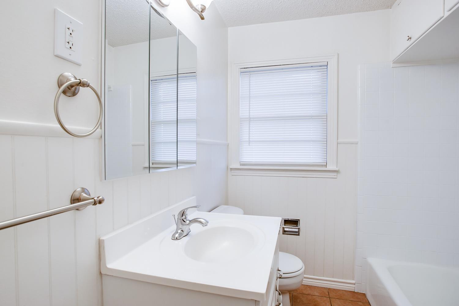 3414 32nd Street Lubbock, TX 79410 - Photo 9 of 11 a bathroom with a sink a toilet and a shower