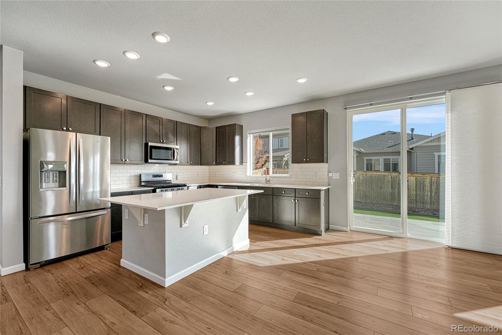 15902 Stringhalt Way Parker, CO 80134 - Photo 16 of 48 a large kitchen with stainless steel appliances granite countertop a stove a refrigerator and a sink with wooden floor