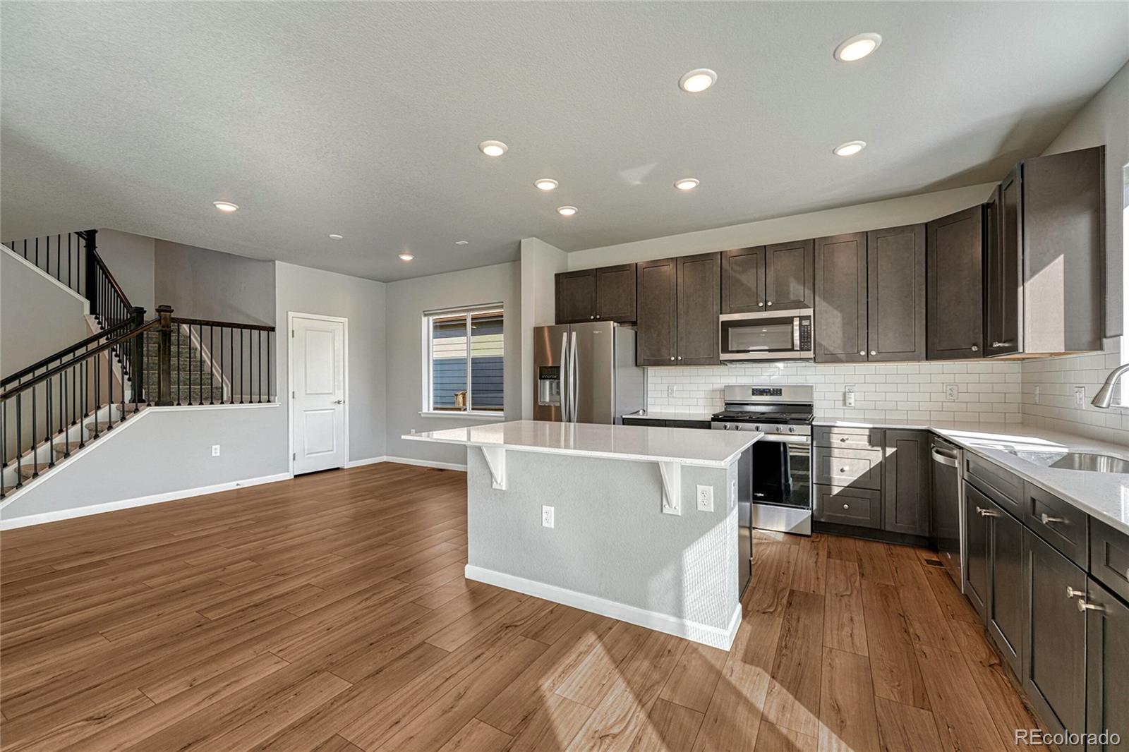 15902 Stringhalt Way Parker, CO 80134 - Photo 17 of 48 a kitchen with stainless steel appliances granite countertop a refrigerator a stove top oven a sink and dishwasher with wooden floor