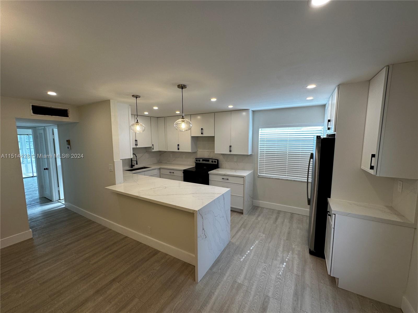 a large kitchen with a large counter top a sink stainless steel appliances and cabinets