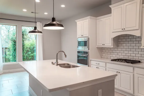 a kitchen with a sink a stove top oven and cabinets