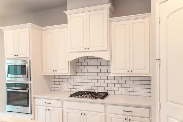 a kitchen with white cabinets and appliances