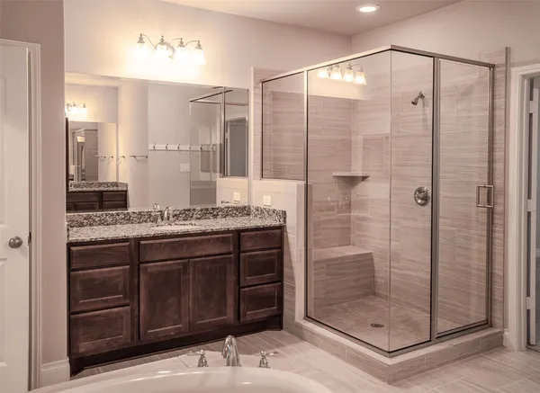 a bathroom with a granite countertop sink a mirror and shower