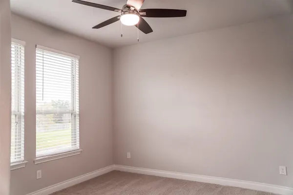 an empty room with a window and a fan