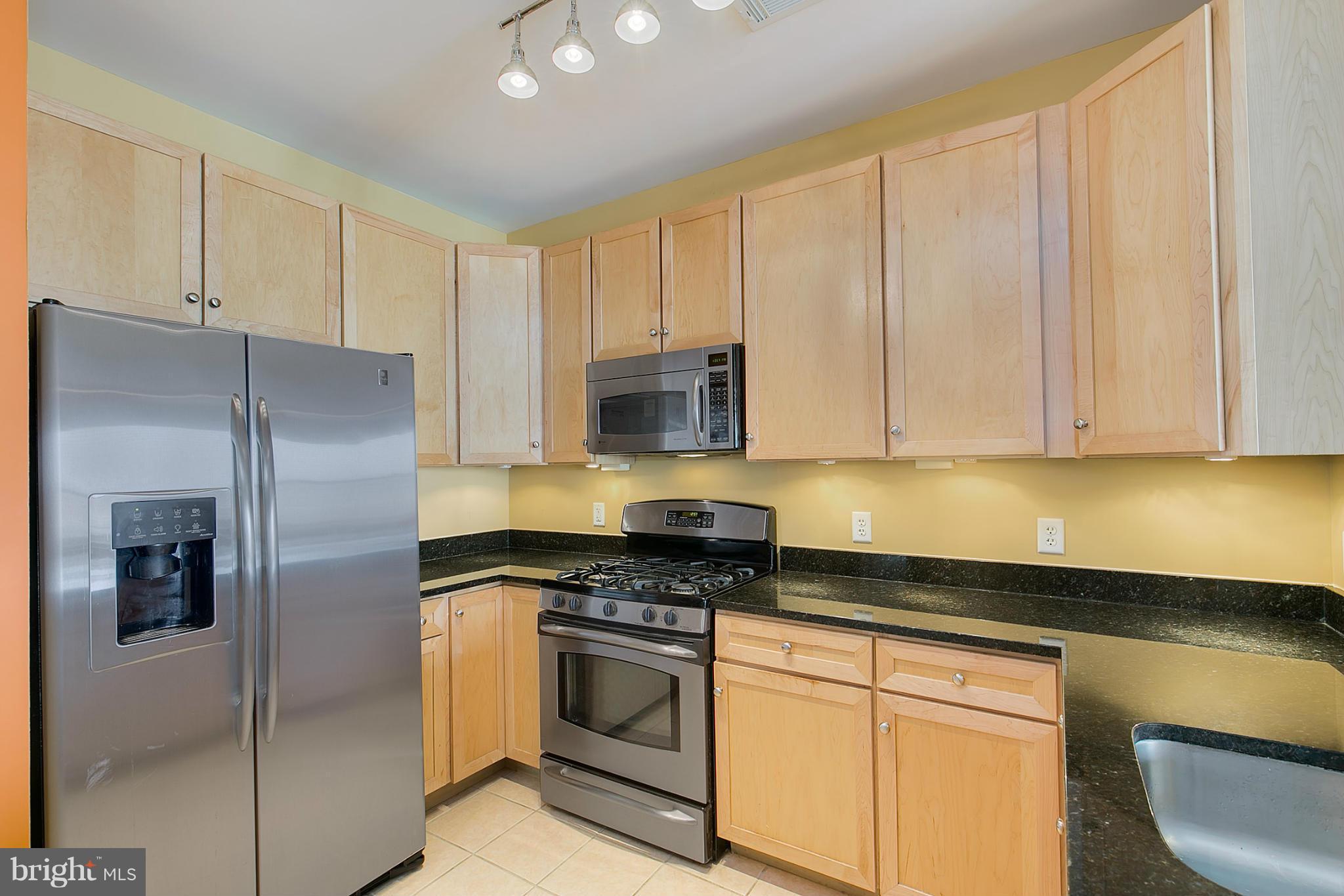 8045 Newell Street, Unit 513 Silver Spring, MD 20910 - Photo 5 of 21 a kitchen with granite countertop white cabinets and stainless steel appliances
