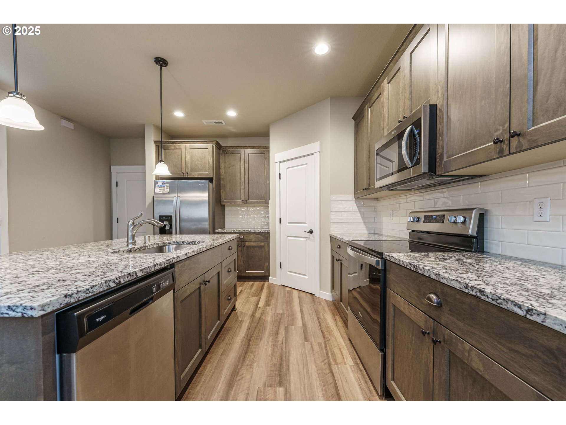 7135 South 13th Street Ridgefield, WA 98642 - Photo 7 of 40 a kitchen with stainless steel appliances granite countertop a sink a stove and a wooden floors
