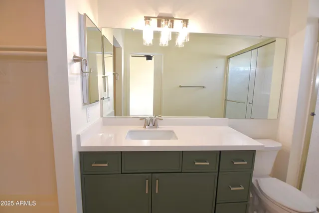 a bathroom with a granite countertop sink a toilet and a mirror