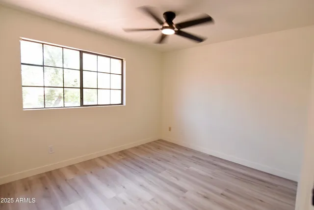an empty room with a window and a fan