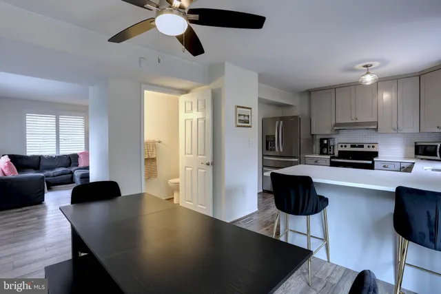 a living room with stainless steel appliances furniture a rug and a view of kitchen