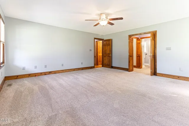 a view of an empty room with chandelier fan