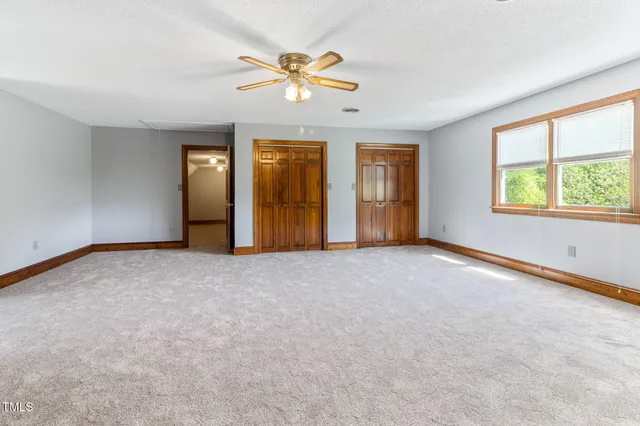 an empty room with windows and ceiling fan