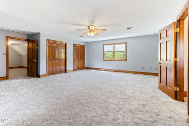 an empty room with windows and chandelier fan